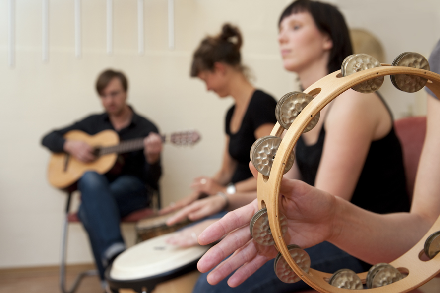 Vier Menschen in Reihe mit Gitarre, Trommel, Tomborin
