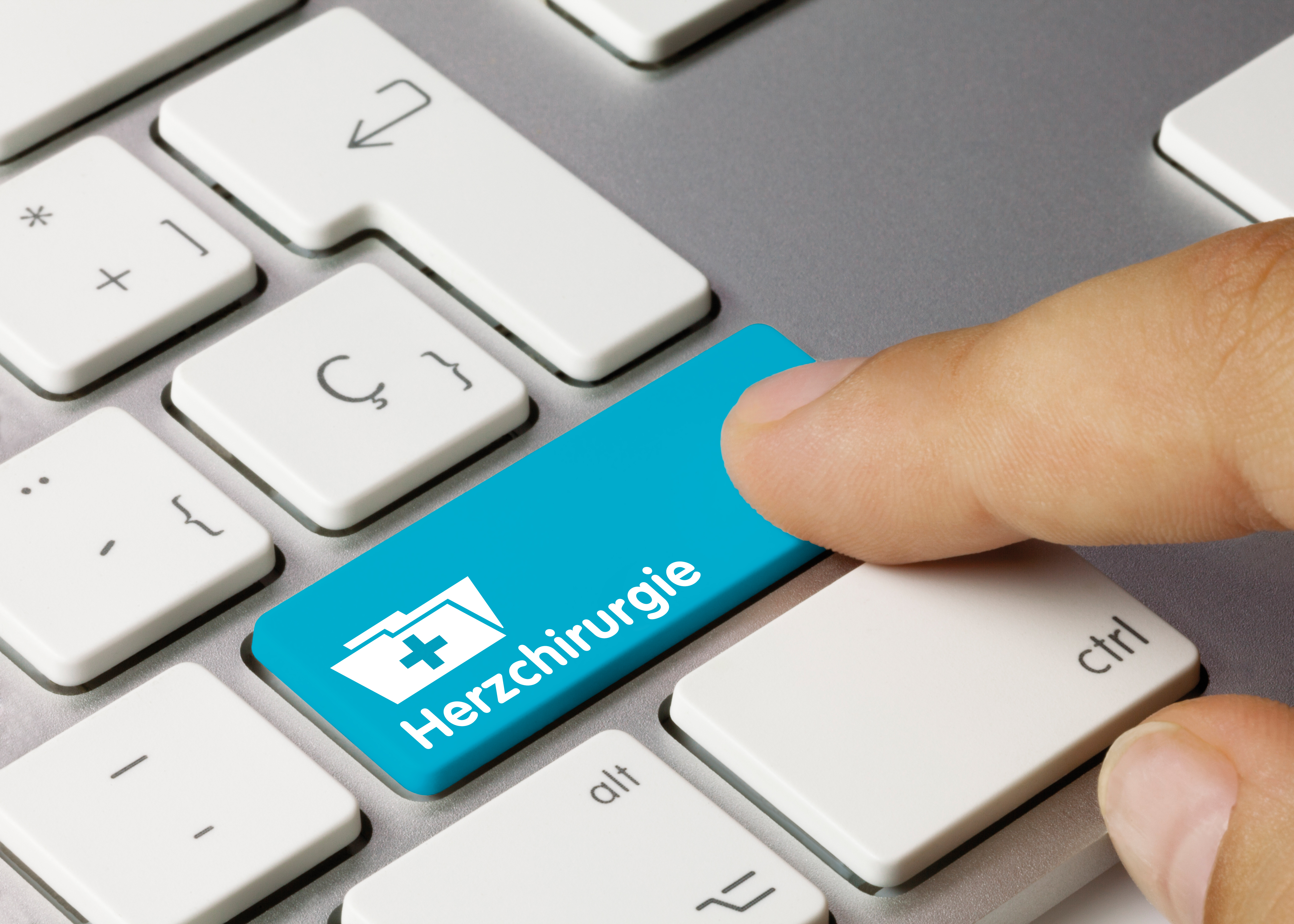 Tastatur mit einer blauen Taste für Herzchirurgie, diese wird von einem Finger berührt