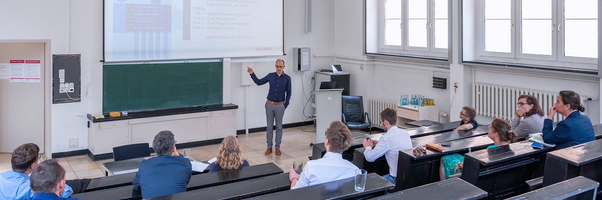 Lehrveanstaltung in einem Hörsaal mit Studierenden und enem Lehrenden an einer digitalen Tafel