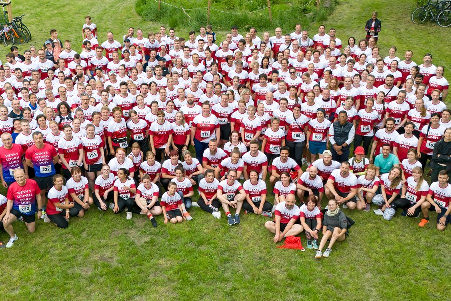 Eine große Menschenmenge in rot-weißen Shirts steht auf einer Wiese  Eine große Menschenmenge in rot-weißen Shirts steht auf einer Wiese