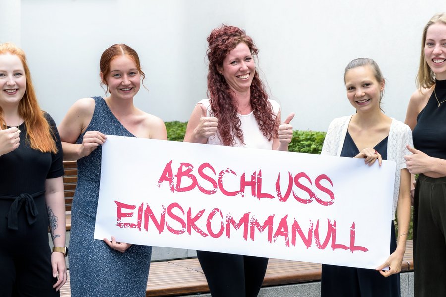 5 junge Frauen stehen nebeneinander und halten ein Banner. Aufschrift: abschluss einskommanull!  5 junge Frauen stehen nebeneinander und halten ein Banner. Aufschrift: abschluss einskommanull!