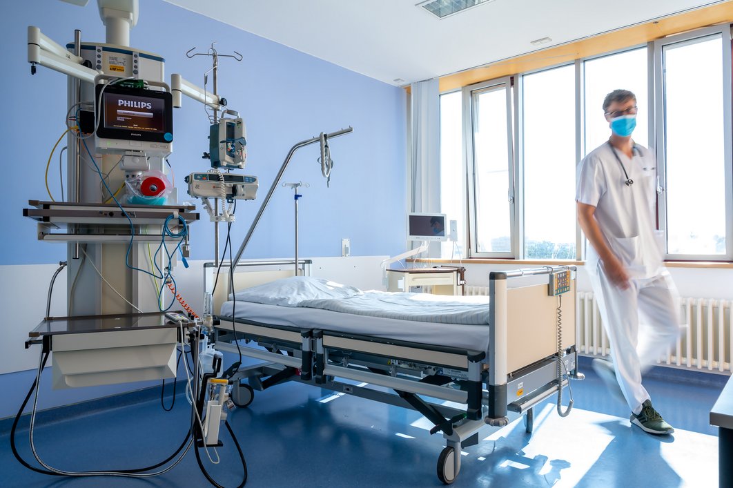 Patientenzimmer mit Überwachungstechnik am Bett, ein Arzt ist im Raum