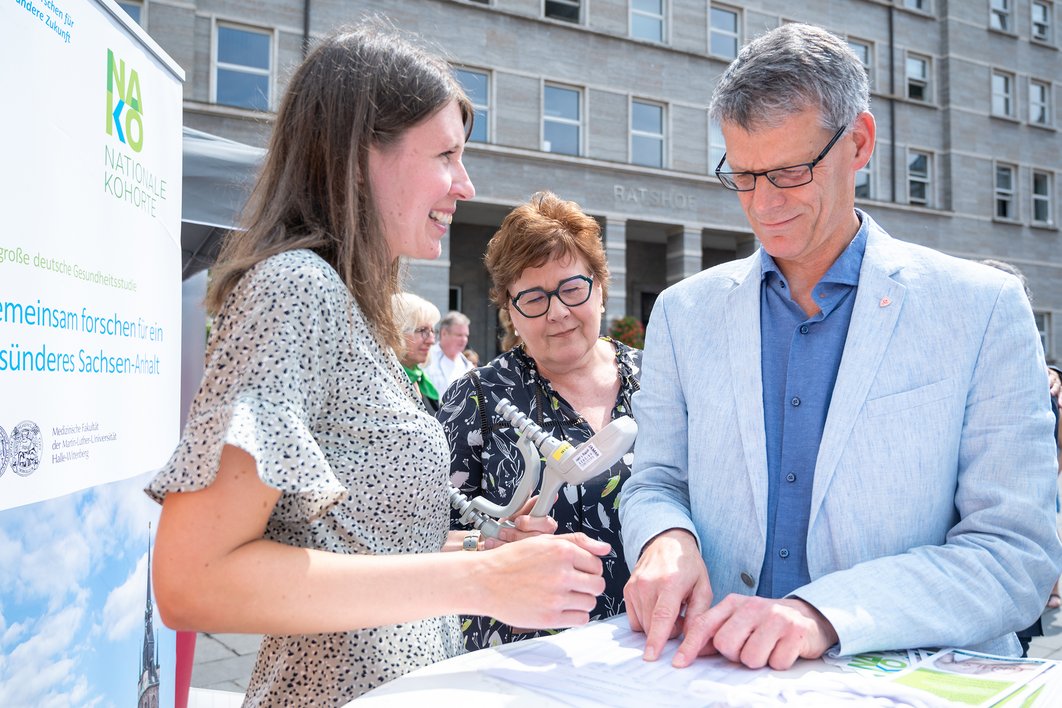 Bürgermeister Egbert Geier steht mit einer Mitarbeiterin der NAKO-Studie und Ministerin Petra Grimm-Benne an einem Stehtisch.
