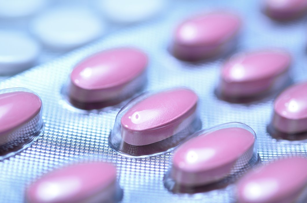Dunkelrote Tabletten in einer Packung, ein Ausschnitt wird gezeigt.