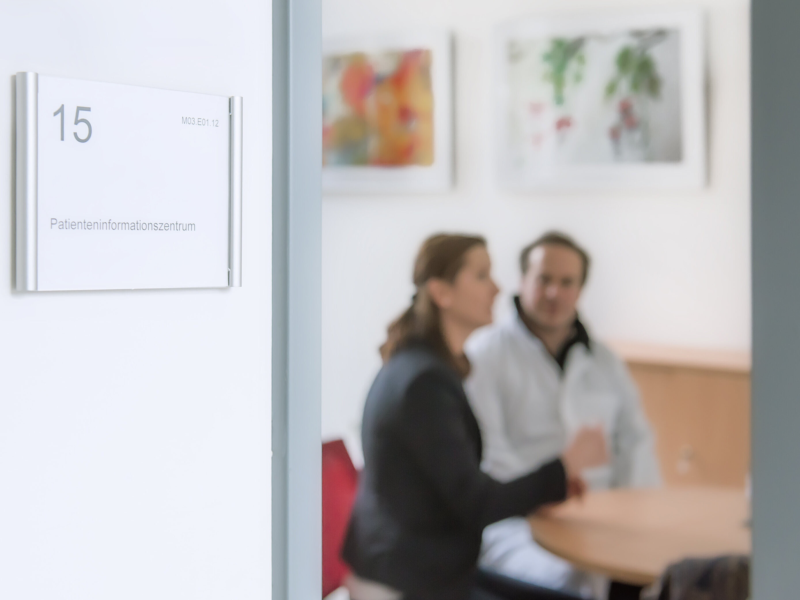 Zwei Personen sitzen an einem Tisch in einem Beratungsraum