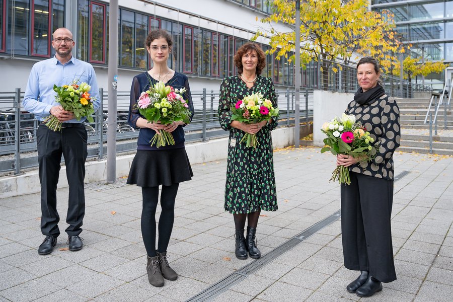 Ein Mann und drei Frauen stehen vor dem Lehrgebäude am Universitätsklinikum. Alle vier haben bunte Blumensträuße in der Hand.   Ein Mann und drei Frauen stehen vor dem Lehrgebäude am Universitätsklinikum. Alle vier haben bunte Blumensträuße in der Hand. 