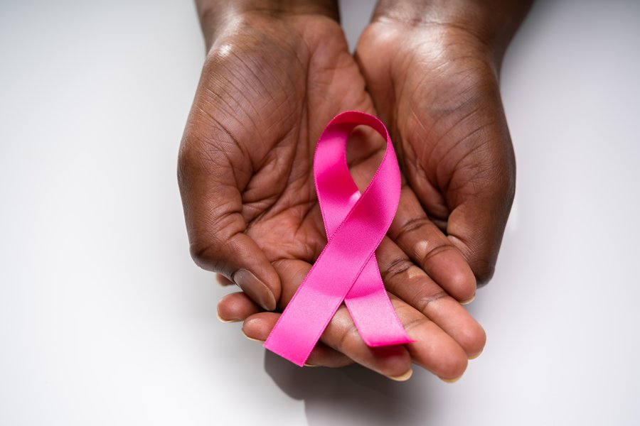 Eine Rose Schleife als internationales Symbol für Brustkrebs in den Händen eines Schwarzen Menschen.   Eine Rose Schleife als internationales Symbol für Brustkrebs in den Händen eines Schwarzen Menschen. 
