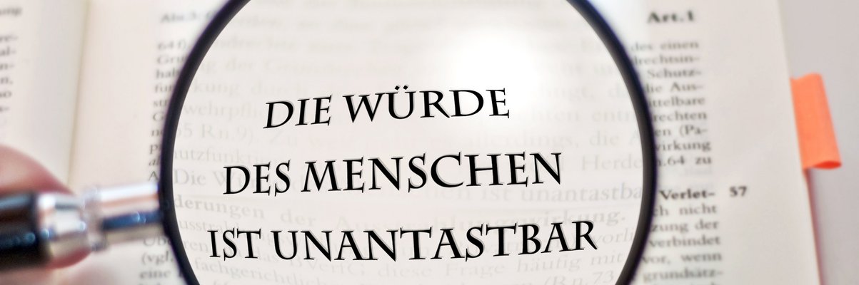 Lupe über dem Schriftzug: Die Würde es Menschen ist unantastbar