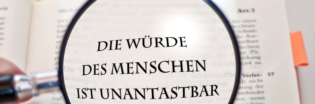 Lupe über dem Schriftzug: Die Würde es Menschen ist unantastbar