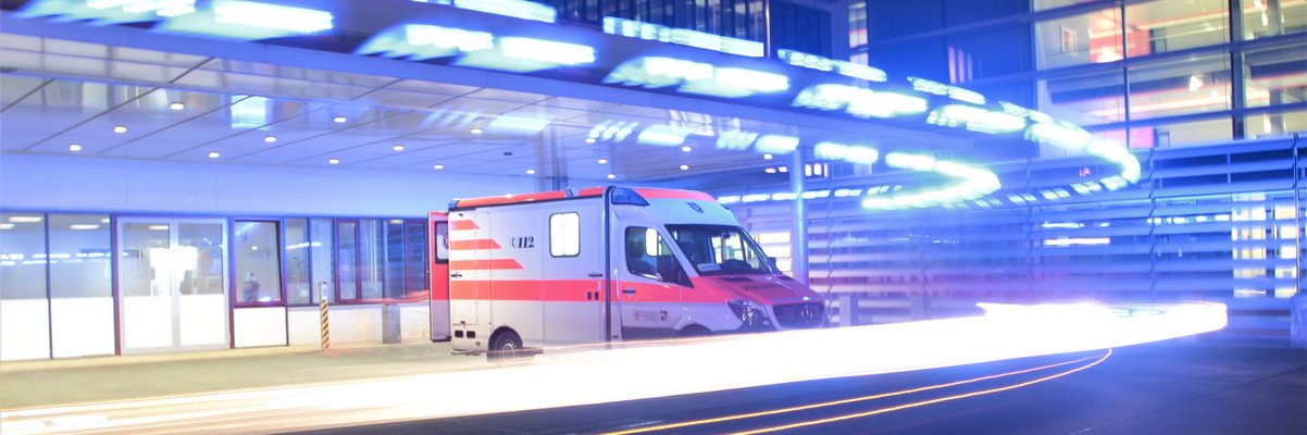 Rettungswagen steht bei Nacht in der beleuchteten Einfahrt zur Notaufnahme