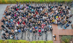 Fast 300 Personen stehen in einem Innenhof der Universitätsmedizin Halle und schauen fast senkrecht nach oben, zum Fotografen. 