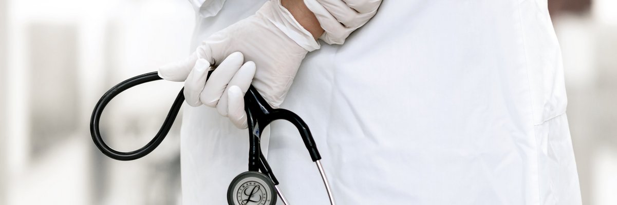 Mediziner hält ein Stetoskop mit verschränkten Armen auf dem Rücken
