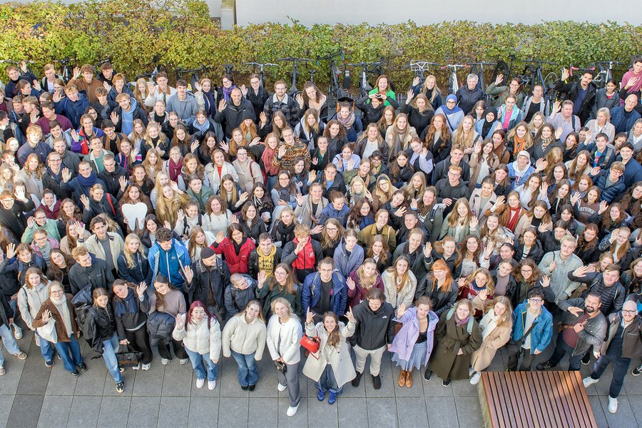 Gruppenbild aus der Vogelperspektive von mehreren hundert Personen, die nach oben schauen. Alle tragen verschiedenfarbige Jacken, wodurch die Gruppe sehr bunt wirkt. Rundherum sind Büsche und Fahrräder zu sehen.  Gruppenbild aus der Vogelperspektive von mehreren hundert Personen, die nach oben schauen. Alle tragen verschiedenfarbige Jacken, wodurch die Gruppe sehr bunt wirkt. Rundherum sind Büsche und Fahrräder zu sehen.