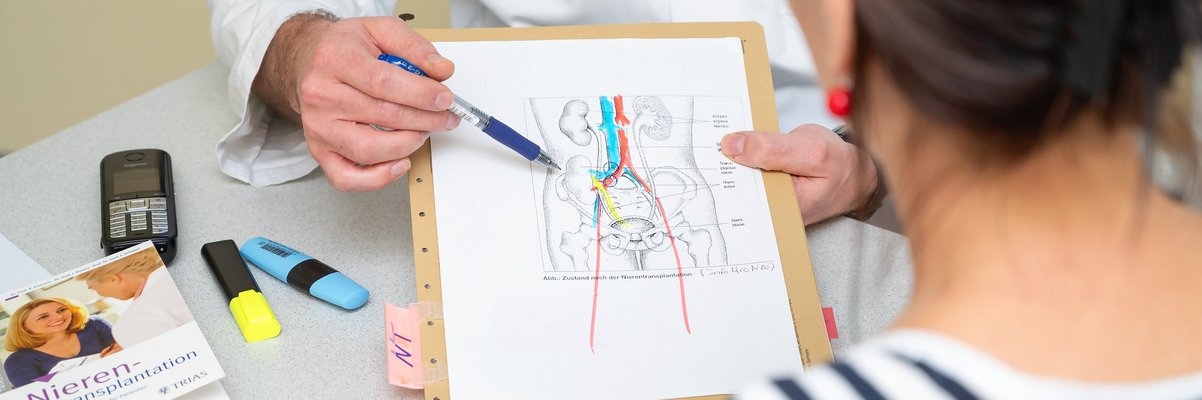 Ein Arzt erklärt anhand einer Grafik einer Patientin eine Behandlung