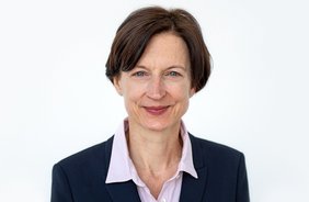 Simone Hettmer blickt frontal in die Kamera und lächelt leicht. Sie hat blaue Augen und trägt halblange brünette Haare.