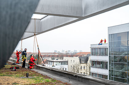 Feuerwehrkräfte sichern auf zwei sich gegenüber liegenden Klinikdächern eine Abseilaktion.