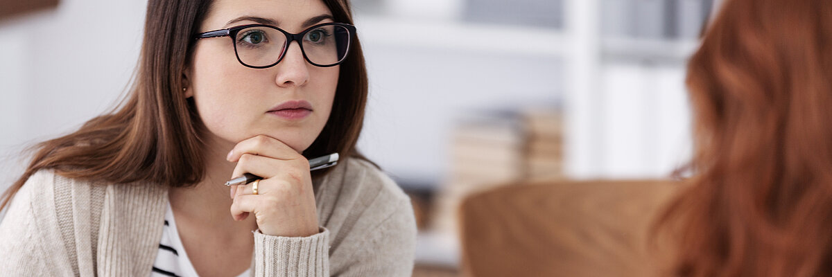 Zwei Frauen sitzen sich gegenüber am Tisch in einer Beratungssituation