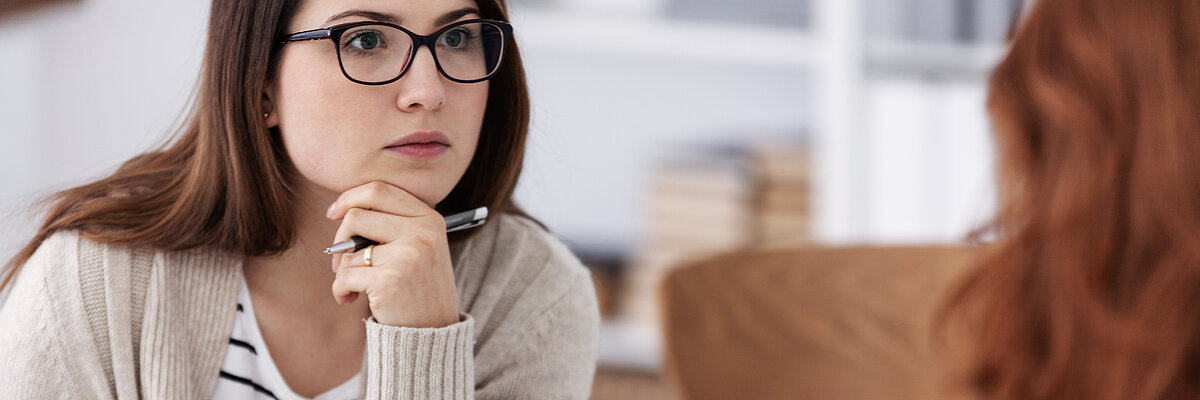 Zwei Frauen sitzen sich gegenüber am Tisch in einer Beratungssituation