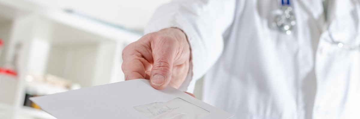 Mediziner mit Stetoskop übergibt ein Blatt Papier