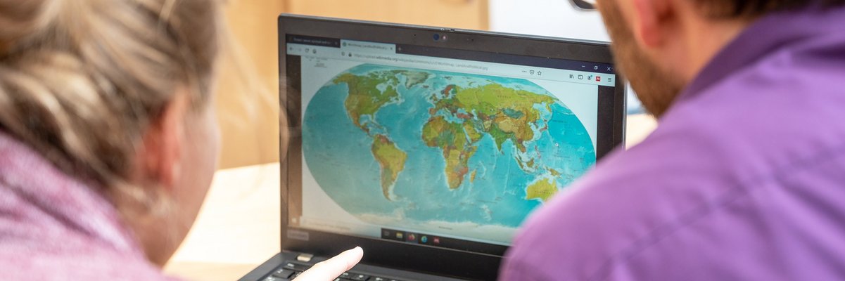 Zwei Menschen schauen sich eine Weltkarte auf dem Laptop an