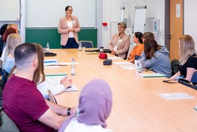 Pflegedirektorin Christine Becker steht vorne in einem Seminarraum und begrüßt die neuen Auszubildenden.