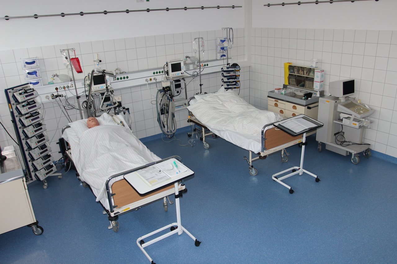 Simulationsraum: Zwei Krankenhausbetten nebeneinander und allerlei medizinische und technische Geräte. In einem Bett liegt eine Dummy-Puppe.