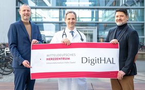 Drei Männer halten ein Schild in die Kamera, das den Projektnamen "DigitHAL" trägt.