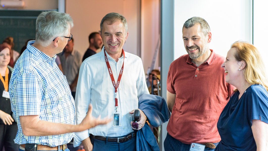 Prof. Dr. Andreas Simm, Marco Tullner, Andreas Beblacz und Prof. Dr. Heike Kielstein (von links) stehen in einem Halbkreis, unterhalten sich und lachen.