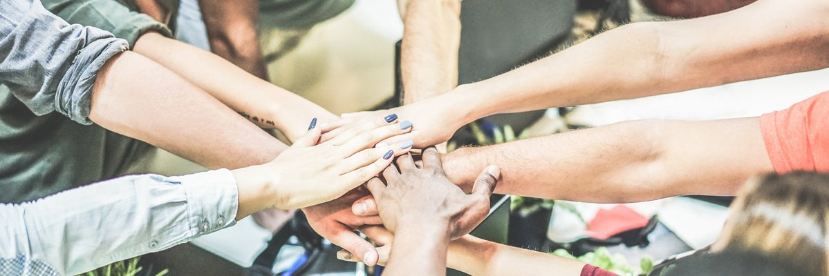 Arme mehrerer Menschen sind zur Mitte ausgestreckt und bilden einen Kreis