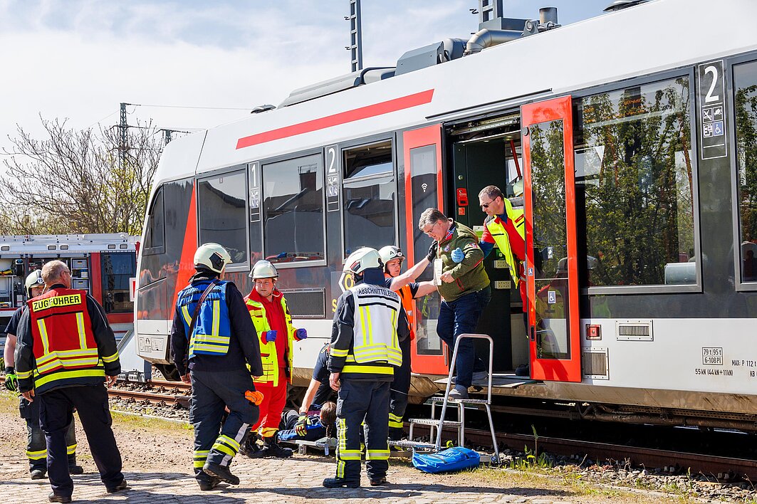 Rettungsteams evakuieren Fahrgäste aus einem Zug.