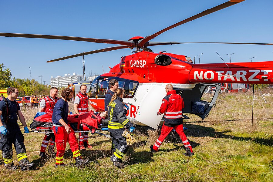 Rettungsteams transportieren eine verletzte Person auf einer Trage zu einem Rettungshubschrauber.  Rettungsteams transportieren eine verletzte Person auf einer Trage zu einem Rettungshubschrauber.