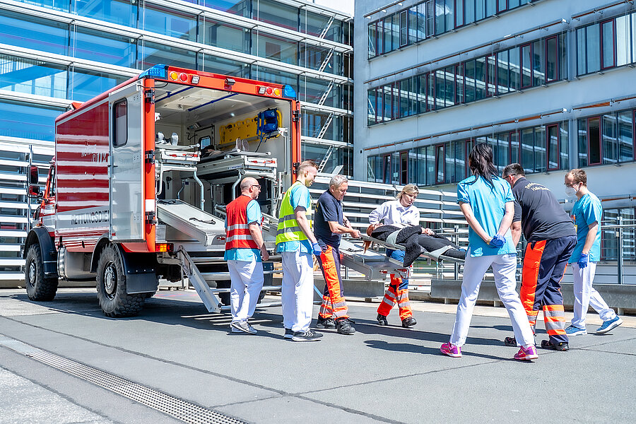 Einsatzkräfte der Feuerwehr und Mitarbeitende der Universitätsmedizin Halle versorgen eine Person auf einer Trage und schieben sie in ein Rettungsfahrzeug der Feuerwehr.   Einsatzkräfte der Feuerwehr und Mitarbeitende der Universitätsmedizin Halle versorgen eine Person auf einer Trage und schieben sie in ein Rettungsfahrzeug der Feuerwehr. 