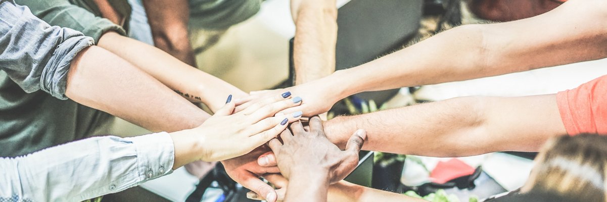 Arme, die von im Kreis stehenden Menschen zur Mitte gestreckt werden