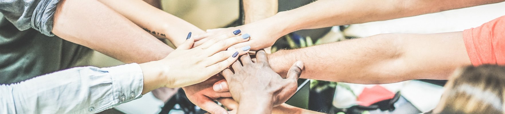 Arme, die von im Kreis stehenden Menschen zur Mitte gestreckt werden