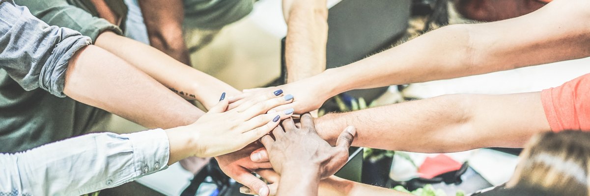 Arme, die von im Kreis stehenden Menschen zur Mitte gestreckt werden