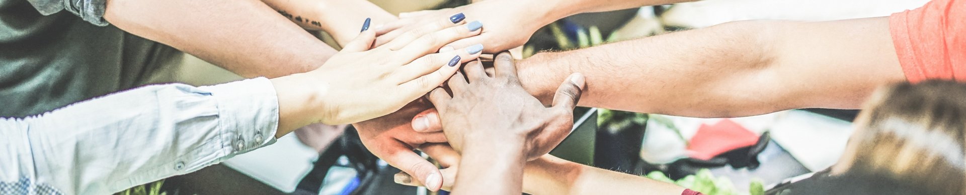 Arme, die von im Kreis stehenden Menschen zur Mitte gestreckt werden