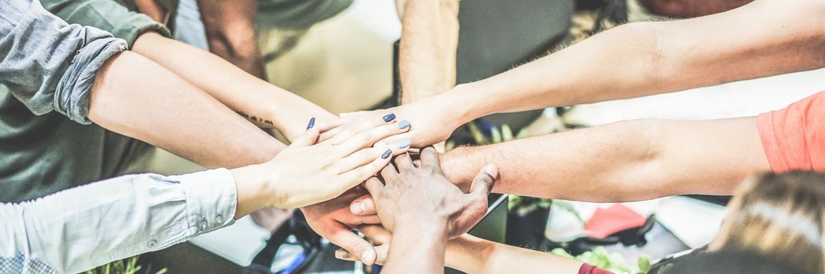 Arme, die von im Kreis stehenden Menschen zur Mitte gestreckt werden