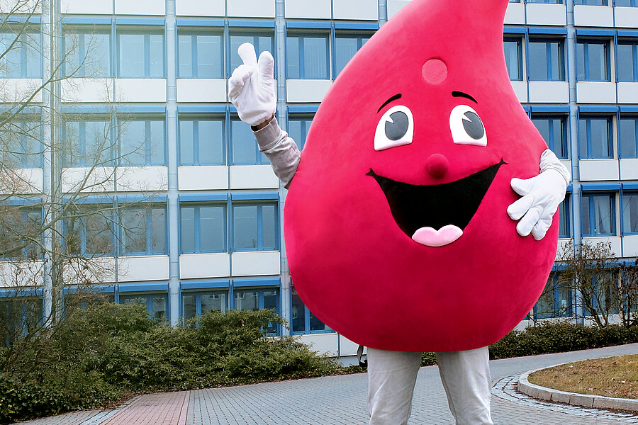 Das Maskottchen der Blutspende des Universitätsklinikums Halle (Saale), ein großer Blutstropfen mit Gesicht, steht vor dem Verlagsgebäude der MZ in Halle (Saale). Es handelt sich um ein mehrstöckiges Bürogebäude. Auf dem Dach steht der Schriftzug „Mitteldeutsche Zeitung“.  Das Maskottchen der Blutspende des Universitätsklinikums Halle (Saale), ein großer Blutstropfen mit Gesicht, steht vor dem Verlagsgebäude der MZ in Halle (Saale). Es handelt sich um ein mehrstöckiges Bürogebäude. Auf dem Dach steht der Schriftzug „Mitteldeutsche Zeitung“.