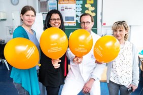 Das Projektteam hält Luftballons in die Kamera.