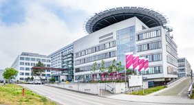 Hauptgebäude des Universitätsklinikums Halle (Saale). Davor wehen Fahnen mit dem Logo.