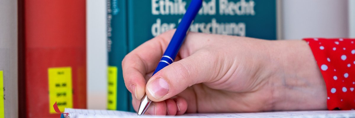 Person schreibt mit einem Stift