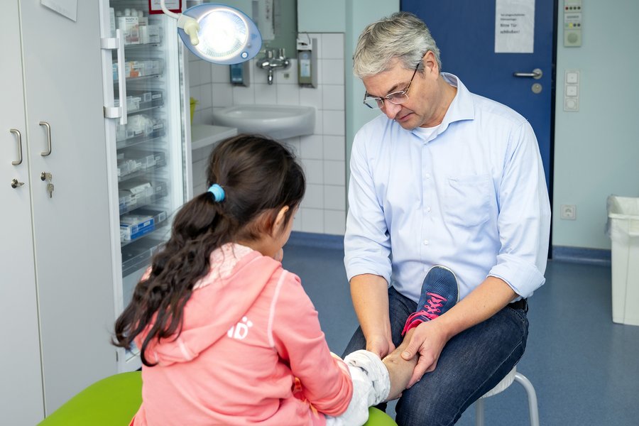 Prof. Dr. Martin Kaiser untersucht das Bein eines Mädchens in einem Untersuchungsraum des Universitätsklinikums Halle (Saale).  Prof. Dr. Martin Kaiser untersucht das Bein eines Mädchens in einem Untersuchungsraum des Universitätsklinikums Halle (Saale).