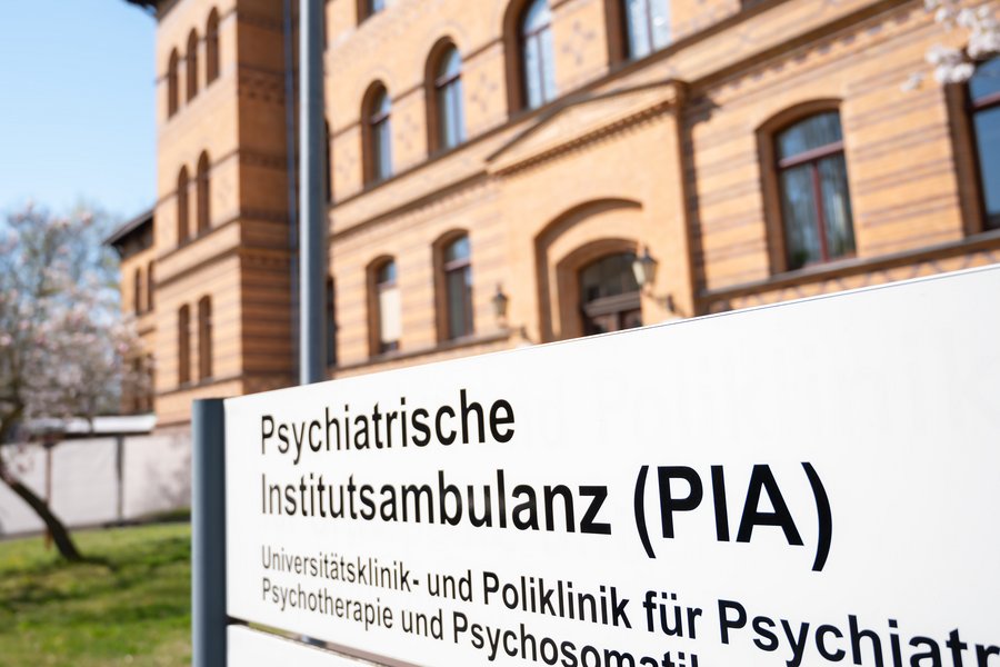 Vor einem Backsteingebäude steht ein Hinweisschild. Darauf steht Psychiatrische Institutsambulanz (PIA)  Vor einem Backsteingebäude steht ein Hinweisschild. Darauf steht Psychiatrische Institutsambulanz (PIA)