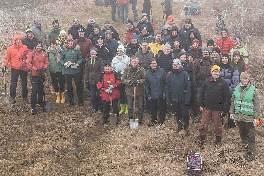 Eine Gruppe von Menschen in Outdoor-Kleidung aus der Vogelperspektive. Sie stehen auf einer Wiese. Es ist neblig.  Eine Gruppe von Menschen in Outdoor-Kleidung aus der Vogelperspektive. Sie stehen auf einer Wiese. Es ist neblig.