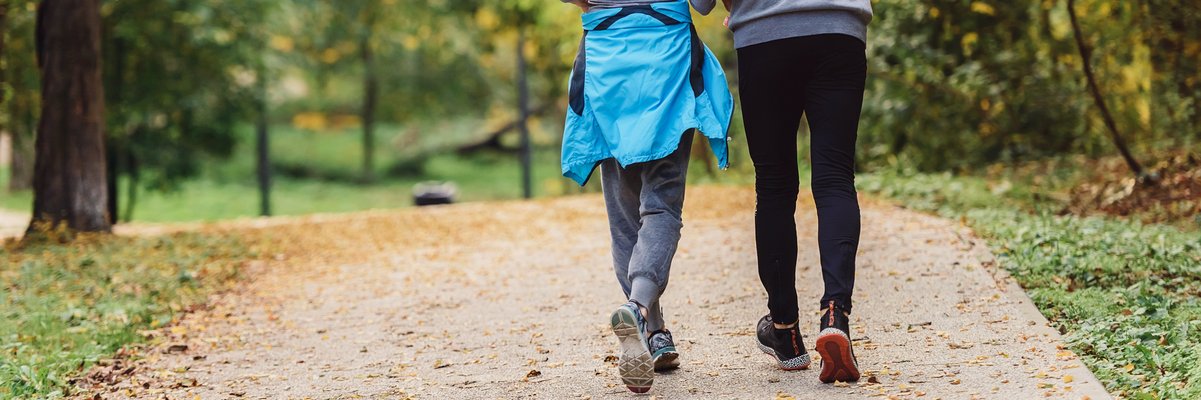 Ein Mann und eine Frau laufen in Sportsachen durch den Wald