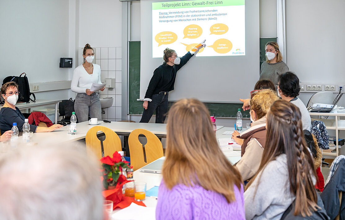 Tagung an einem u-förmigem Tisch und einer Darstellung auf der Leinwand