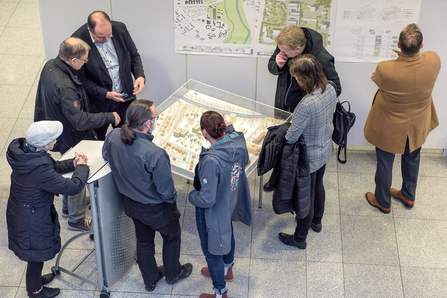 Das Foto blickt auf acht Personen herab, die sich das Modell des Erstplatzierten im städtebaulichen Wettbewerb zum Theoretikum anschauen.   Das Foto blickt auf acht Personen herab, die sich das Modell des Erstplatzierten im städtebaulichen Wettbewerb zum Theoretikum anschauen. 